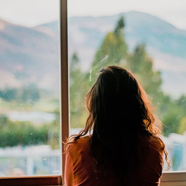 Person meditating calmly by a window with natural light.