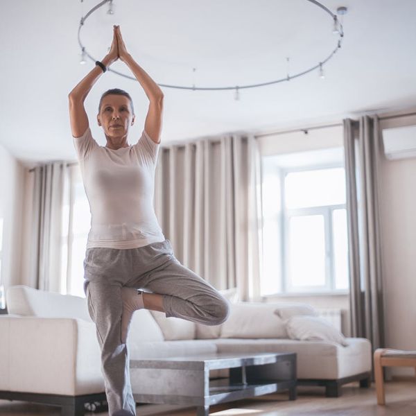 Person stretching on a yoga mat in a bright, pearl-white room.